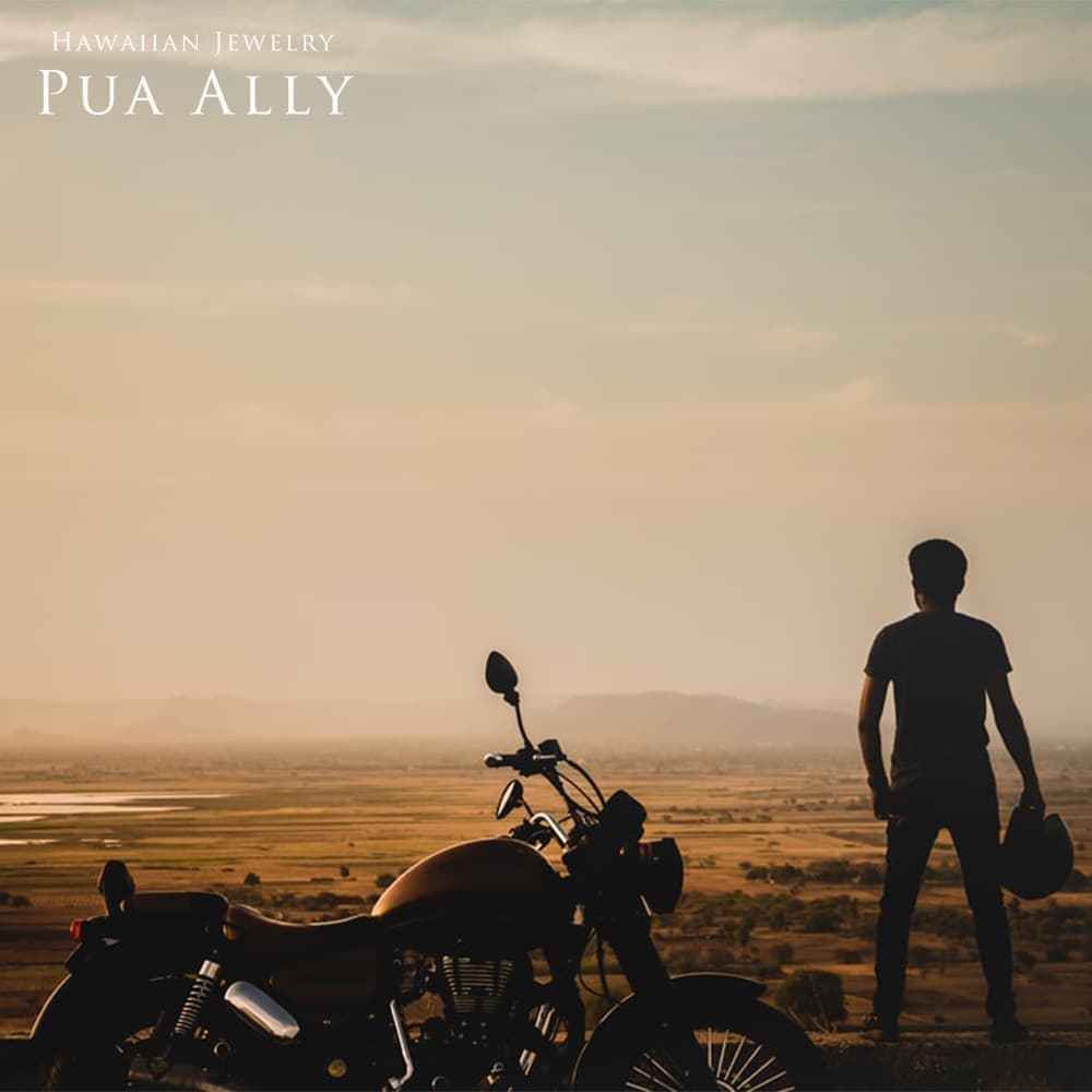 アメリカの風景に男性とバイクが映っている写真 男性はバイクの横に立っていてヘルメットを手に持っている